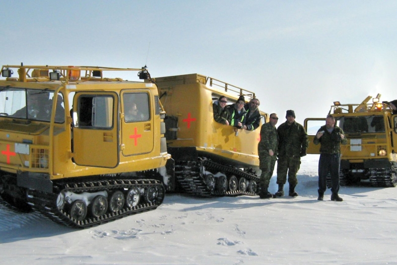 CBO employees with two yellow BV206 all-terrain vehicles with track wheels on snow in the Arctic.